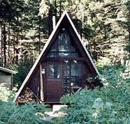 Kook Lake Cabin is a wooden A-frame structure with a metal roof and Plexiglass windows in both ends Large
